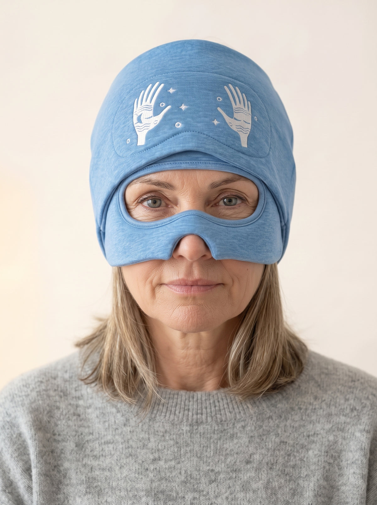 The same woman with the eye cover slid up, looking through the eye opening of the cap.