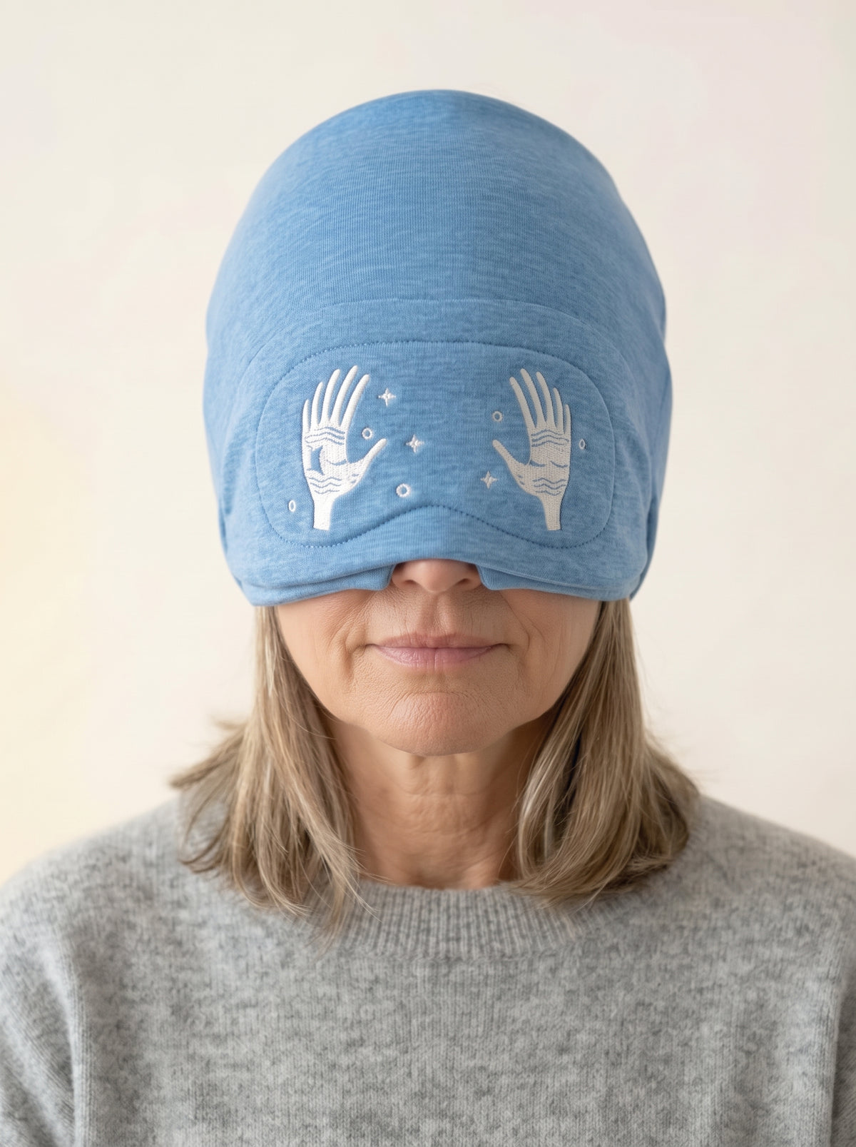 Woman sitting upright wearing the Moonwraps cap with the eye cover down.